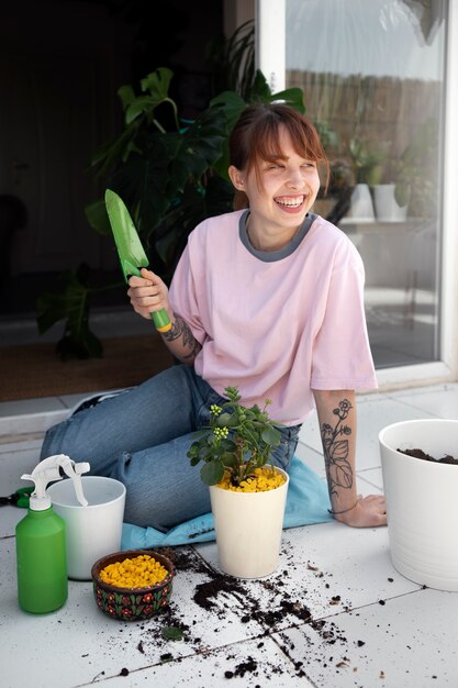 Smiley-Frau mit vollem Schuss, die Pflanzen umpflanzt