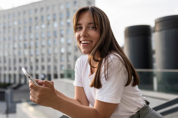 Smiley-Frau posiert, während sie ihr Telefon hält