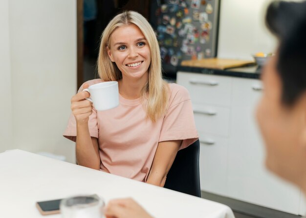 Smiley-Frau zu Hause während der Pandemie eine Tasse Kaffee mit ihrem Freund