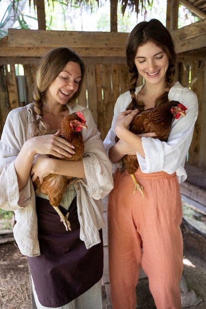 Kostenloses Foto smiley-frauen der vorderansicht, die hühner halten