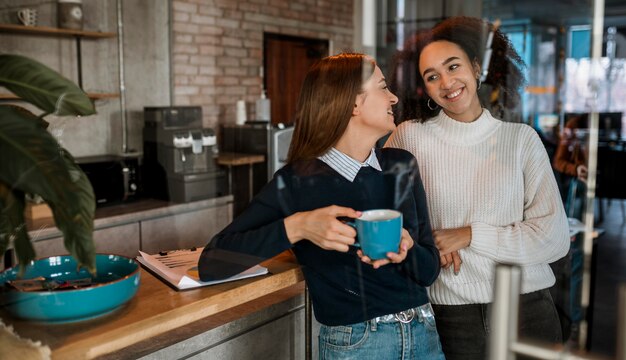 Smiley-Frauen, die während eines Treffens Kaffee trinken