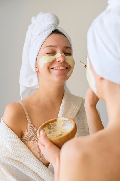 Smiley-Frauen, die zu Hause Gesichtsmasken anwenden