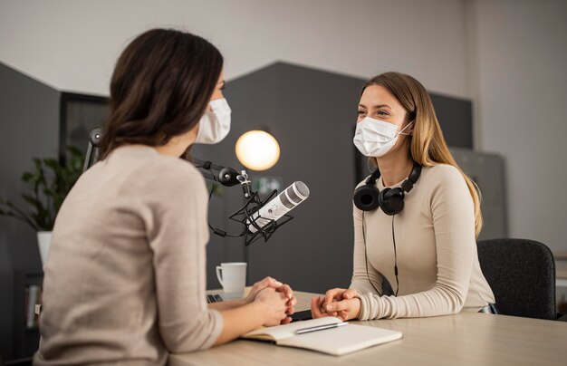 Smiley-Frauen machen Radio mit medizinischen Masken