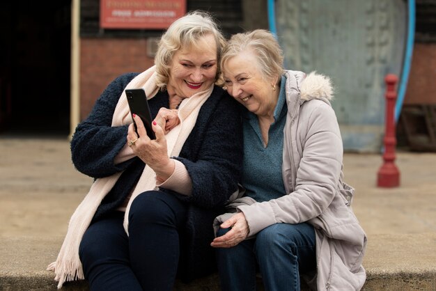 Smiley-frauen mit mittleren schüssen und smartphones