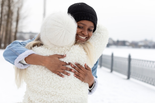 Kostenloses Foto smiley-frauen mit mittlerer aufnahme, die sich im freien umarmen