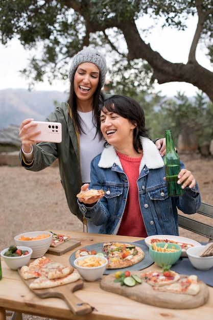 Smiley-Frauen mit mittlerer Aufnahme und Pizza