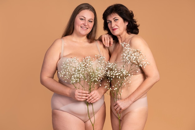 Smiley-Frauen posieren mit Blumen mittlerer Aufnahme