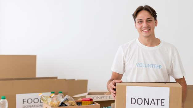 Smiley-Freiwilliger, der eine Spendenbox mit Kopienraum hält