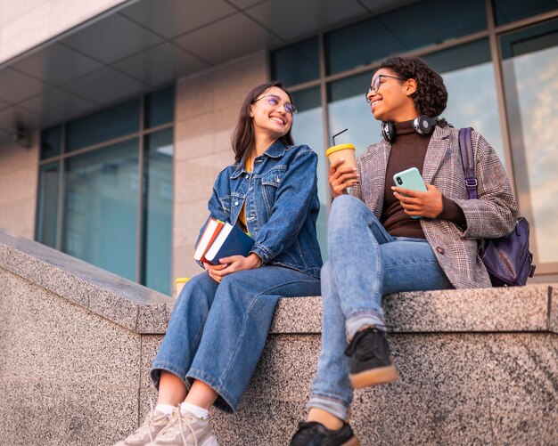 Smiley-Freunde mit Büchern, die zusammen Kaffee trinken