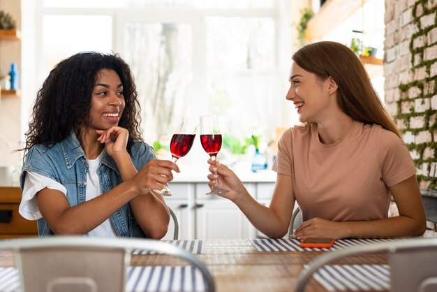 Smiley-Freundinnen rösten zusammen ein Glas Wein