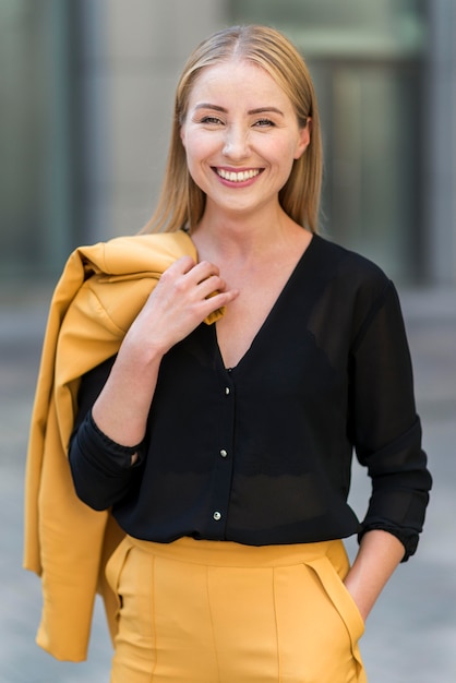 Kostenloses Foto smiley-geschäftsfrau, die draußen im anzug aufwirft