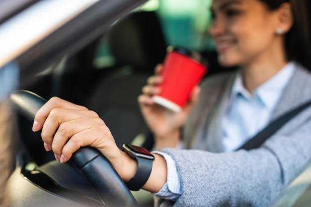 Smiley Geschäftsfrau, die ihren Kaffee während der Fahrt trinkt