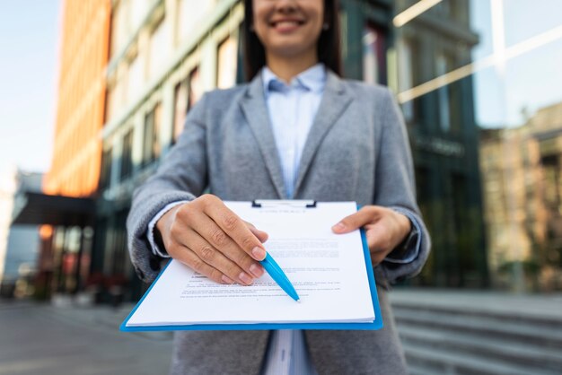 Smiley-Geschäftsfrau zeigt Ihnen, wo Sie in der Zwischenablage unterschreiben können