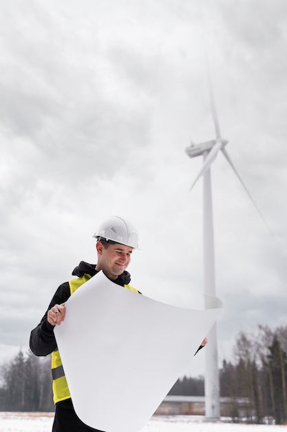 Smiley-Ingenieur mit mittlerem Schuss, der einen Plan hält