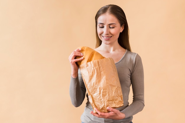 Smiley junge Frau, die Papiertüte mit Brot hält