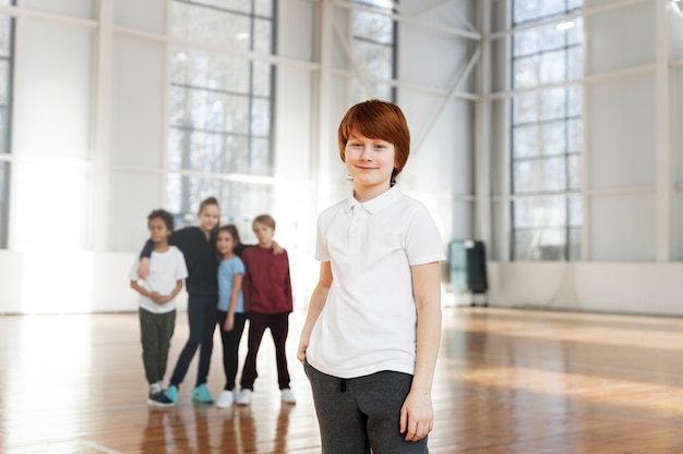 Smiley-Junge im Fitnessstudio, der Vorderansicht aufwirft