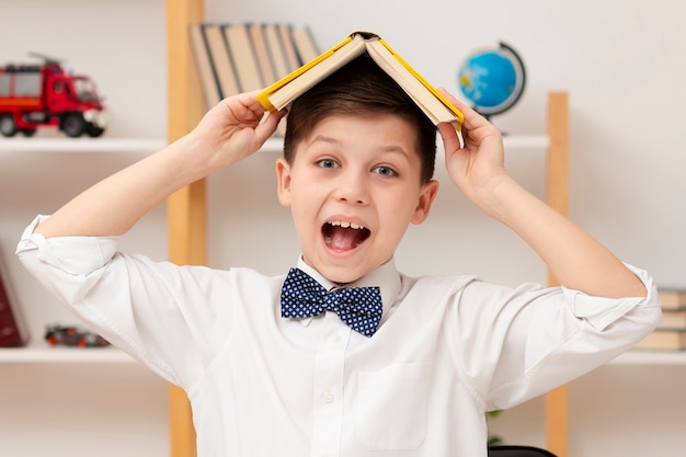 Smiley-Junge mit Buch auf dem Kopf
