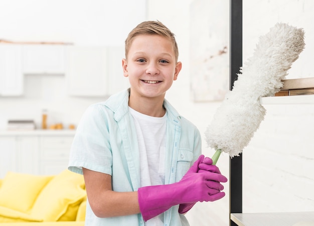 Smiley-Junge posiert, während er Staubtuch hält