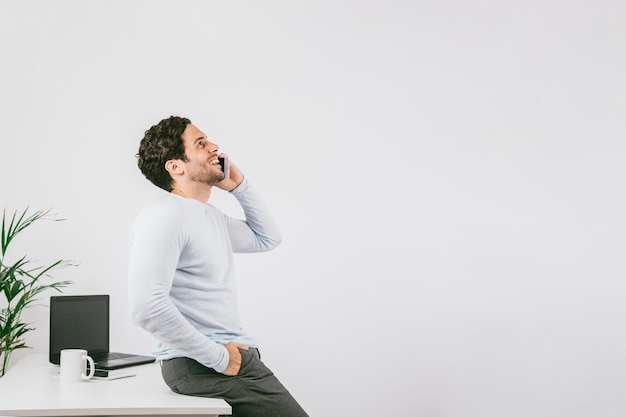 Smiley junger Mann im Büro sprechen am Telefon