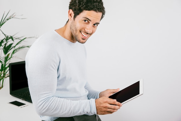 Smiley junger Mann posiert mit talblet im Büro