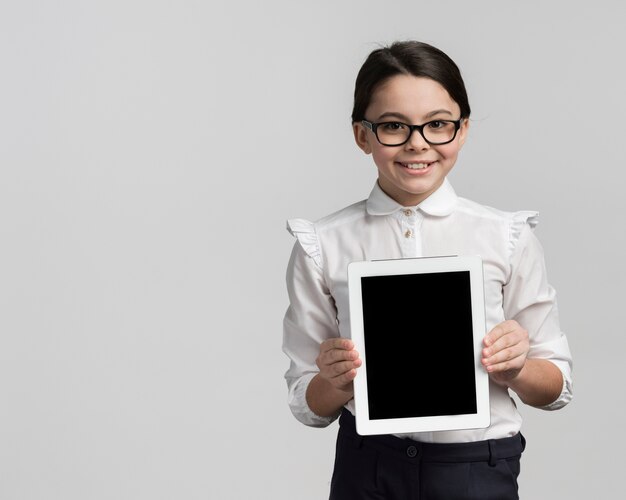 Smiley junges Mädchen, das Tablette mit Kopienraum hält