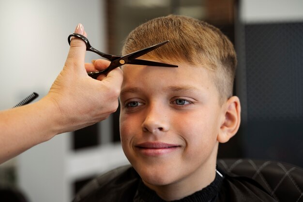 Smiley-Kind bekommt Haarschnitt bei Seitenansicht des Salons