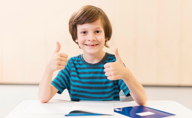 Kostenloses Foto smiley-kind, das das daumen hoch-zeichen tut