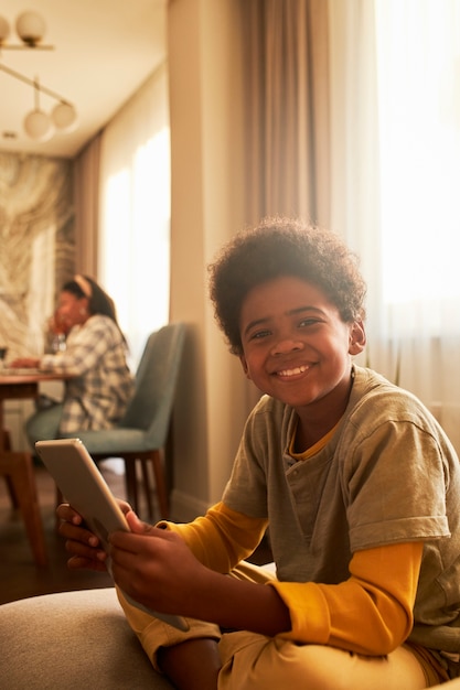 Kostenloses Foto smiley-kind mit mittlerem schuss, das tablet hält