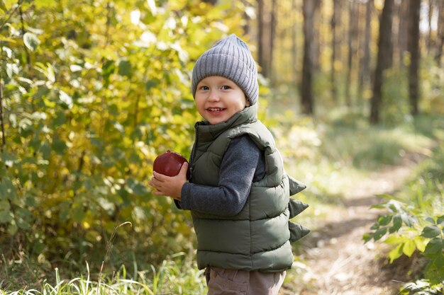 Smiley-Kind mit mittlerem Schuss, der Apfel hält