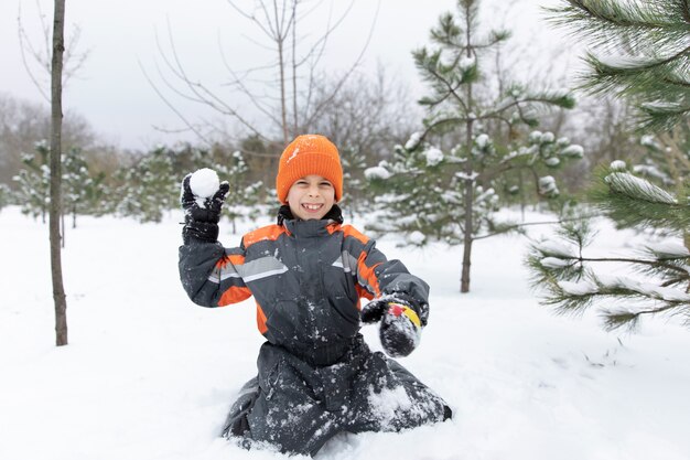 Smiley-Kind mit vollem Schuss, das mit Schnee spielt