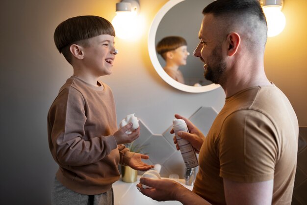 Smiley-Kind und Vater der Seitenansicht im Badezimmer