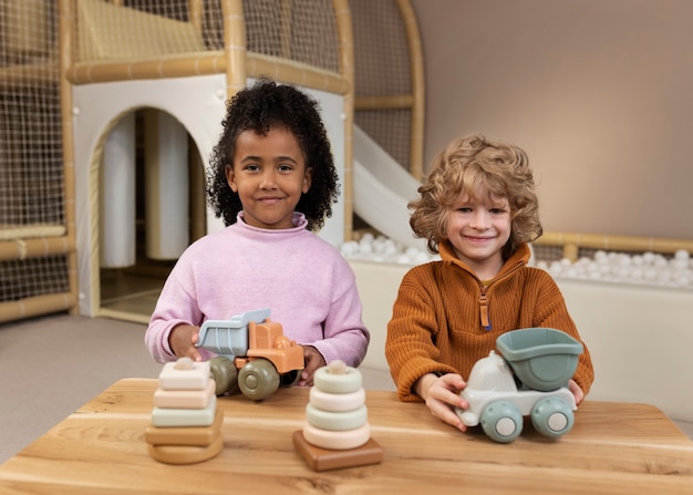 Kostenloses Foto smiley-kinder der vorderansicht, die mit öko-spielzeug spielen