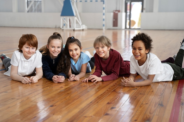 Kostenloses Foto smiley-kinder mit vollem schuss, die auf dem boden liegen