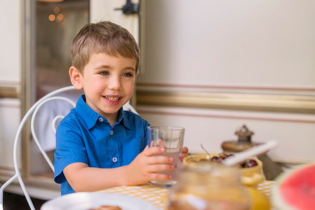 Kostenloses Foto smiley kleiner junge, der ein glas limonade hält