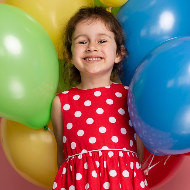 Smiley kleines Mädchen in einem roten Kleid, das ihren Geburtstag feiert