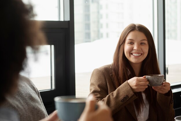 Smiley-Kollegen mit Kaffeetassen bei der Arbeit