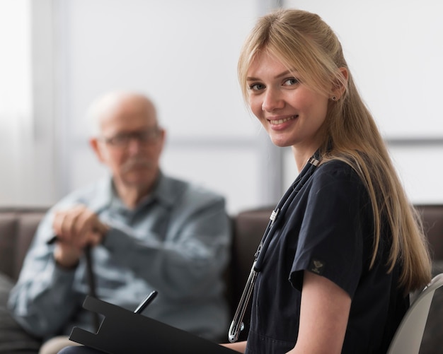 Smiley-Krankenschwester, die mit Mann in einem Pflegeheim aufwirft