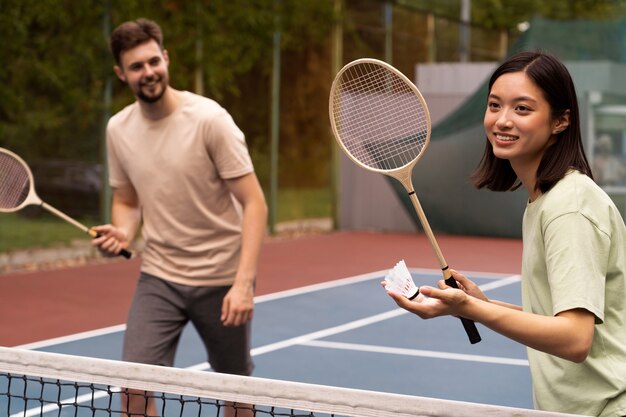Smiley-Leute der Seitenansicht, die Badminton spielen