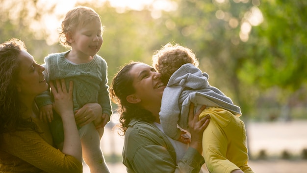 Smiley lgbt Mütter draußen im Park mit ihren Kindern