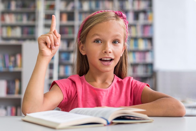 Kostenloses Foto smiley-mädchen, das ihre hausaufgaben in der bibliothek macht