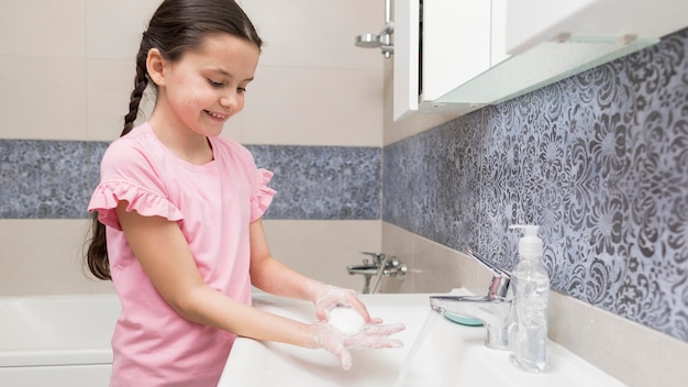 Smiley-Mädchen, das ihre Seitenansicht der Hände wäscht