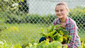 Kostenloses Foto smiley-mädchen, das salatkorb hält