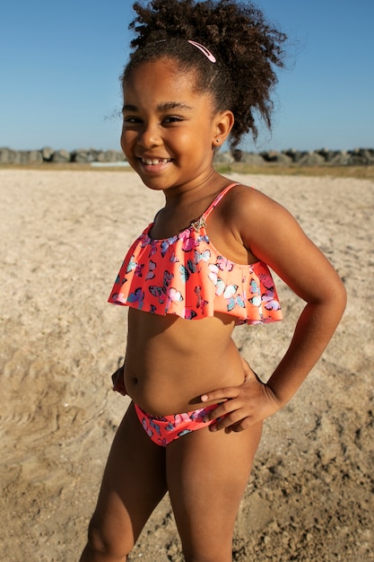 Kostenloses Foto smiley-mädchen der seitenansicht, das am strand aufwirft