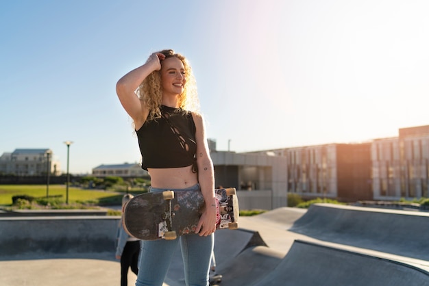 Smiley-mädchen der vorderansicht, das skateboard hält
