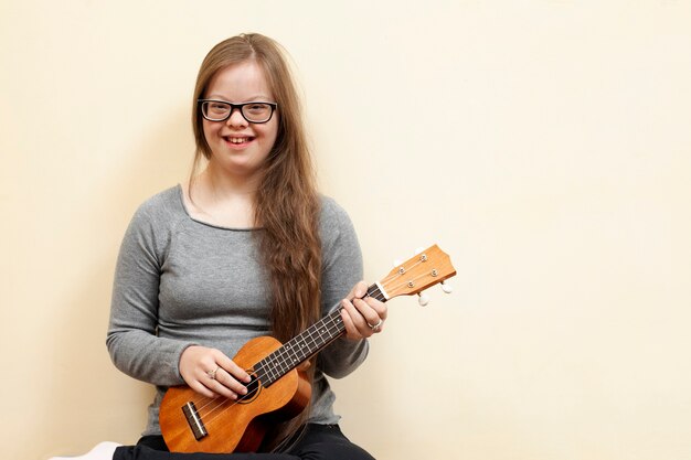 Smiley-Mädchen mit Down-Syndrom hält Gitarre