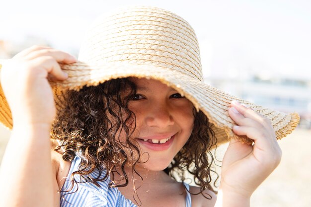 Smiley-Mädchen mit Hut am Strand hautnah