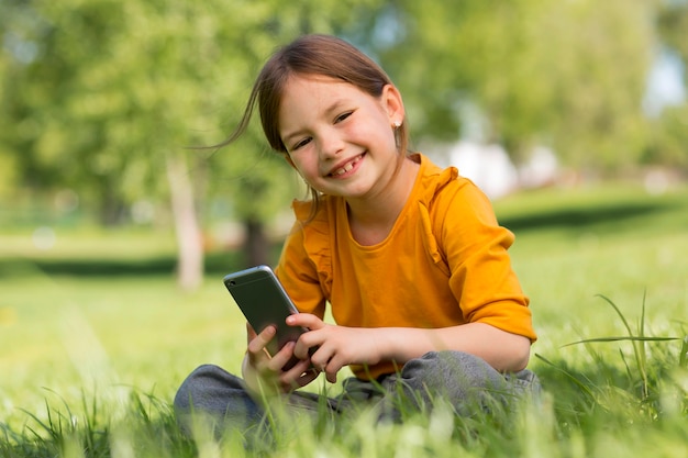 Smiley-Mädchen mit mittlerem Schuss, das Smartphone hält