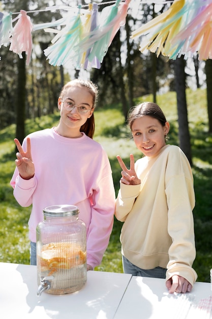 Smiley-Mädchen mit mittlerer Aufnahme und Limonade im Freien