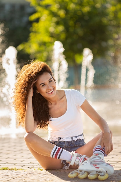 Smiley-Mädchen sitzt und posiert in ihren Rollerblades