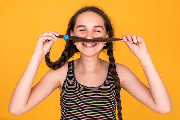 Kostenloses Foto smiley mädchen spielt mit ihren zöpfen